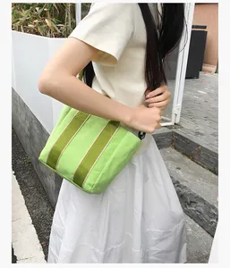 Detail of bright green canvas bucket bag featuring contrasting durable striped web handles