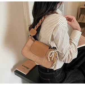 Detail of vintage square bag with braided leather strap and pearl bow charm detail