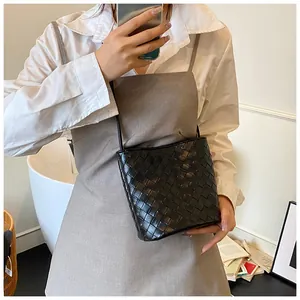 Borsa a secchiello nera intrecciata alla moda con tracolla in un ambiente moderno
