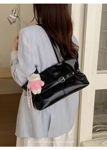 Detail of glossy black patent leather tote bag with metallic buckle and cute bear charm
