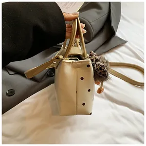 Detail der cremefarbenen Polka-Dot-Handtasche mit Leoparden-Schleife und Plüschball