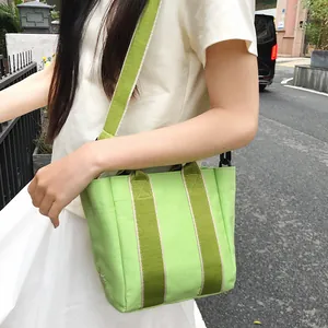 Striped canvas bucket bag in light green and olive with sunflower embroidery detail