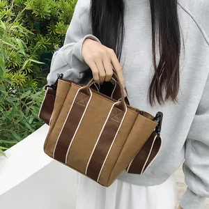 Fashionable striped canvas bucket bag with brown contrast shoulder strap in natural outdoor light