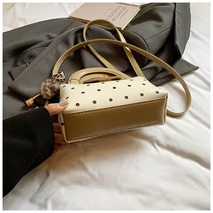 Detailansicht der Retro-Punkt-Handtasche mit khakifarbenen Griffen und Plüsch-Anhänger