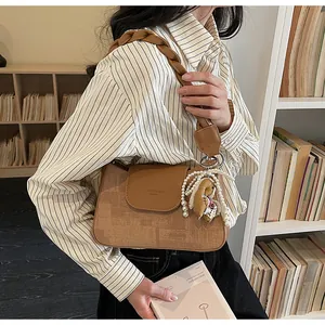 Detail of vintage brown shoulder bag with woven strap, pearl accent and rabbit charm