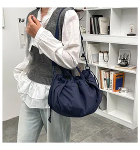 Detail of dark blue pleated tote bag with adjustable drawstring strap worn by model