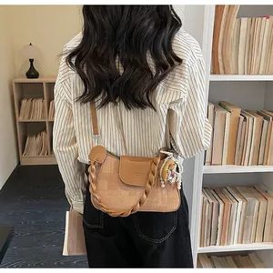 Close-up of retro brown shoulder bag with woven handle and bear pearl pendant detail
