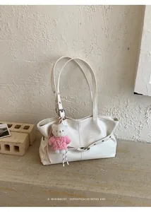Detail view of cream tote bag with soft leather texture and plush bear charm