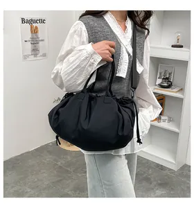 Dettaglio di una borsa tote nera plissettata con tracolla indossata da una modella