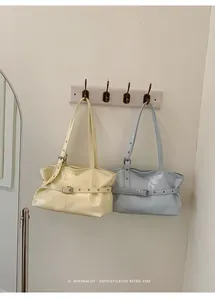 Detail of minimalist leather tote bags in cream and light blue with adjustable straps