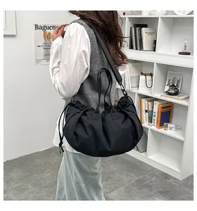 Detail of black pleated tote bag with adjustable straps shown in a lifestyle setting