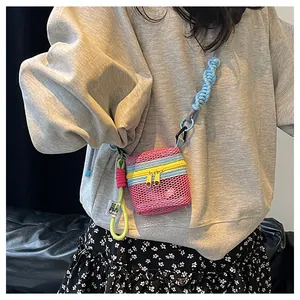 Detail of pink mesh mini bag featuring colorful zippers and thick braided strap on model