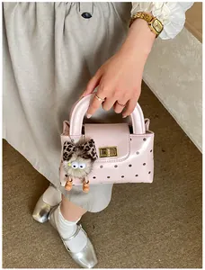 Rosa gepunktete Handtasche mit goldenem Drehverschluss und lustigem Monster-Anhänger