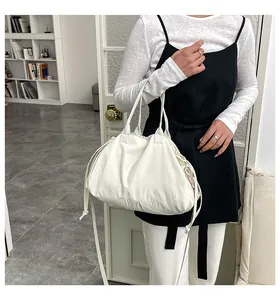 Dettaglio della borsa a sbuffo bianca con coulisse, tessuto a pieghe e fibbie dorate