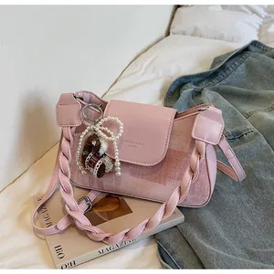 Detailed view of pink leather bag with braided strap, pearl charm and alpaca pendant