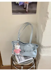 Detail view of light blue tote bag with metallic buckle and cute bear charm pendant