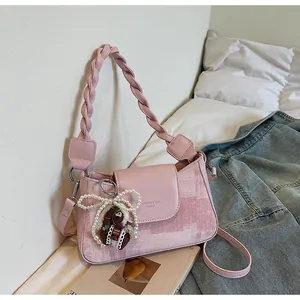 Pink shoulder bag detail showing woven leather handle, pearl bow and pony charm