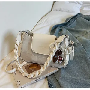 Detail of square vintage bag with leather handle, textured fabric, and charm accessory