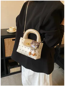 Makro-Detail der cremefarbenen Polka-Dot-Handtasche mit goldenem Drehverschluss und Anhänger