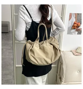 Borsa a secchiello kaki portata a spalla da modella in un ambiente minimalista