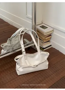Detail view of white leather tote bag featuring belt buckle decor and polished finish