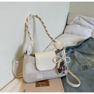 Detailed view of beige checkered handbag with pearl bow and pony pendant on magazine