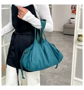 Dettaglio della borsa tote a pieghe verde acqua con coulisse e tracolla in tessuto a contrasto
