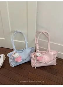 Detail of light blue and pink glossy tote bags with metal eyelets and bear charms