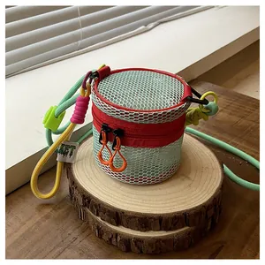 Close-up of mint green mesh mini pouch with red zippers and woven lanyard on wooden stand