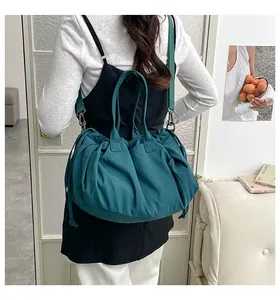 Detail of dark green pleated hobo bag with drawstring and wide strap in artistic setting