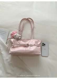 Detail of pink faux leather tote bag featuring adjustable silver eyelet straps and plush charm