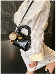 Detail der schwarzen Polka-Dot-Handtasche mit Goldschloss und Plüschtier-Anhänger