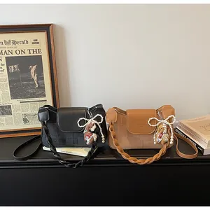 Detail of vintage square shoulder bag with woven strap and decorative horse charm
