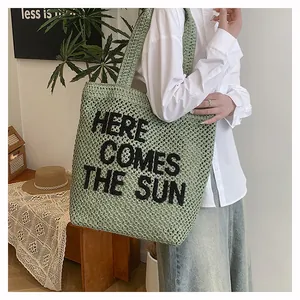 Detail of green knit tote bag with 3D black embroidered text HERE COMES THE SUN