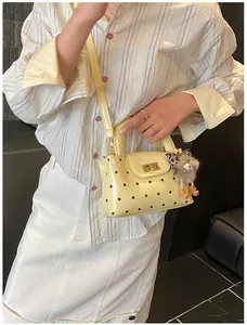 Detail der hellgelben gepunkteten Handtasche mit goldenem Drehverschluss und Plüschanhänger