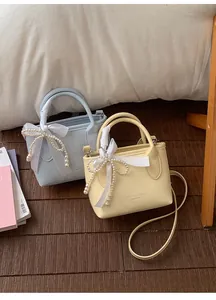 Dettaglio di mini borse a secchiello azzurre e beige con perle e fiocchi decorativi