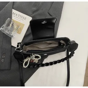 Detailed interior of black PU crossbody bag with grey lining and a pearl charm