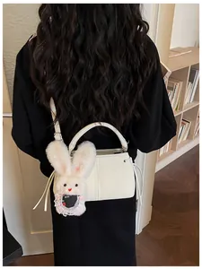 Rear view of a model carrying a white structured handbag with a cute plush rabbit charm