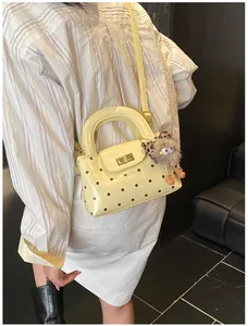 Pünktchen-Handtasche mit Metalldrehverschluss und süßem Plüschanhänger am Outfit