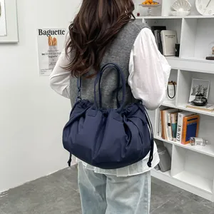 Navy blue pleated tote bag with drawstring closure shown on model in a minimalist room