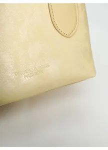 Macro dettaglio della trama in pelle beige con logo di moda impresso sulla borsa