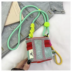 Detail of a mini mesh music pouch with colorful rope strap and woven label on denim