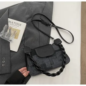 Detail of grey textured fabric bag with black woven leather handle and crossbody strap