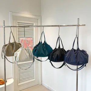 Pleated large tote bags in five colors hanging on a silver rack with minimalist design