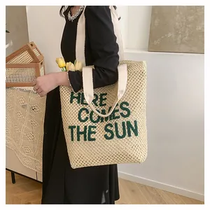 Detail of woven beach tote showing the 'HERE COMES THE SUN' text and canvas strap