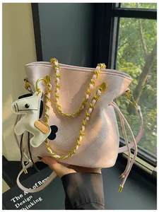 Close-up of pink quilted bucket bag with gold chain and horse charm in soft daylight