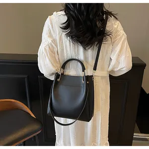 Borsa a secchiello minimalista in pelle nera con manico ad anello indossata da una modella