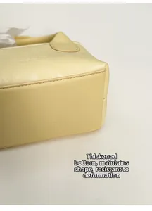Dettaglio del fondo rinforzato di una borsa in pelle beige per mantenere la forma piatta
