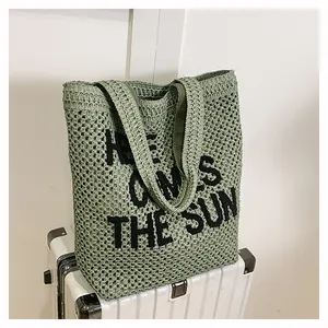 Detail of green crochet tote bag with embroidered Here Comes The Sun text on mesh texture
