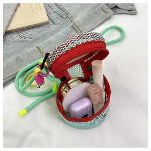 Detailed view of mini mesh crossbody bag holding lipstick and earbuds with rope strap